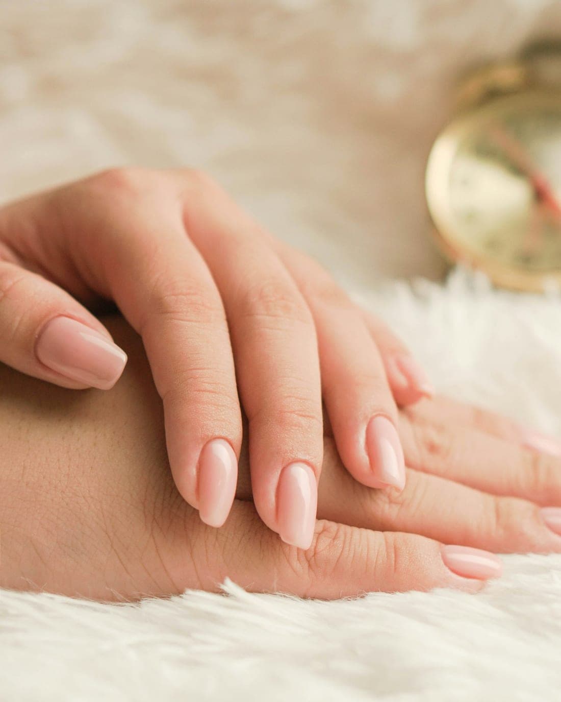 Detalhe de unhas em gel com acabamento nude sob luz suave